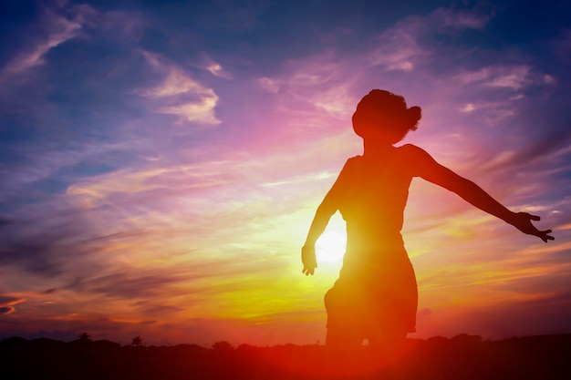 Silhouette einer Frau, die bei Sonnenuntergang gegen den Himmel steht