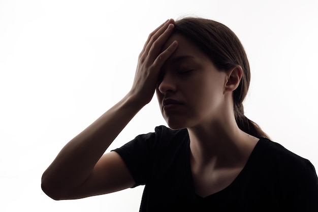 Silhouette einer Frau, die Kopfschmerzen hat, isoliertes Porträt auf weißem Hintergrund