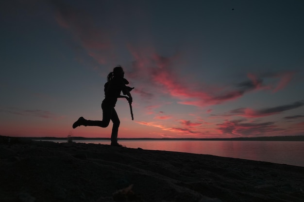 Silhouette einer Frau in Bewegung vor dem Himmel bei Sonnenuntergang. Lifestyle-Thema