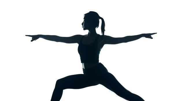 Silhouette einer Frau in einer Yoga-Pose mit ausgestreckten Armen, die Stärke und Flexibilität demonstrieren