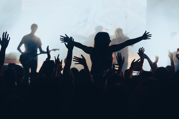 Silhouette einer Frau mit erhobenen Händen bei einem Konzert