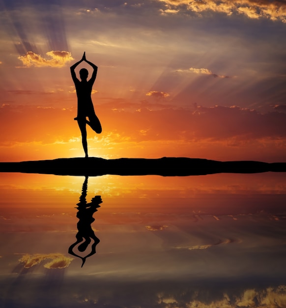 Silhouette einer Frau Yoga am Abend. Frau beim Yoga bei Sonnenuntergang