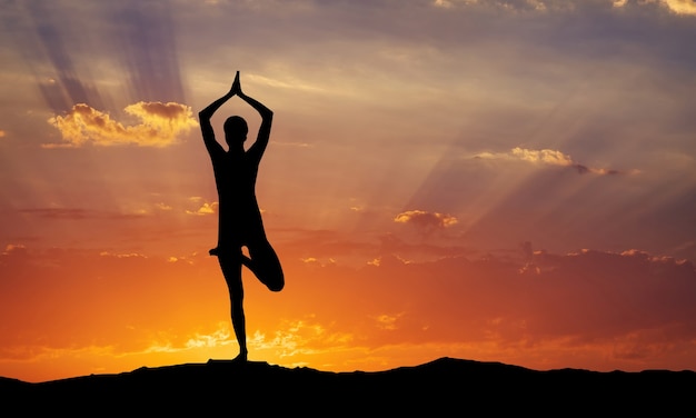 Silhouette einer Frau Yoga am Abend. Frau beim Yoga bei Sonnenuntergang