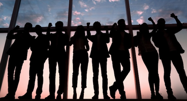 Foto silhouette einer gruppe von geschäftsleuten, die in der nähe des bürofensters stehen