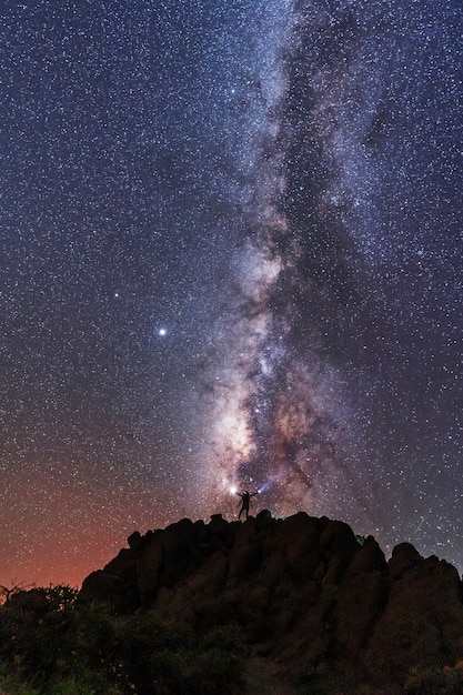 Silhouette einer jungen frau unter den sternen, die die milchstraße in der nacht betrachten, astrofotografie