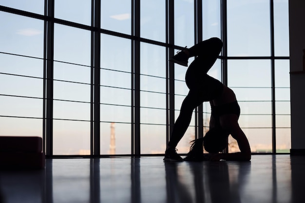 Silhouette einer jungen sportlichen Frau in Sportbekleidung, die Fitness im Fitnessstudio macht.