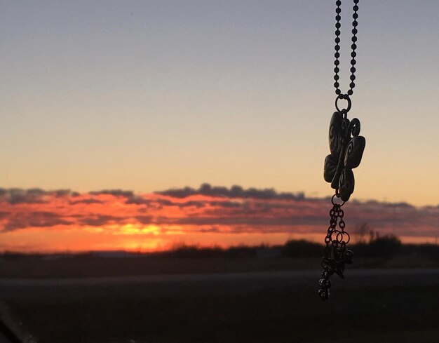 Foto silhouette einer kette, die während des sonnenuntergangs auf dem feld gegen den himmel hängt