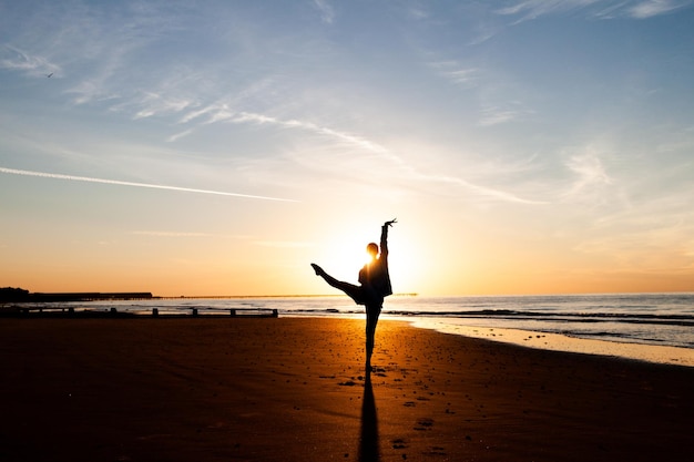 Silhouette einer Person am Strand gegen den Himmel bei Sonnenaufgang