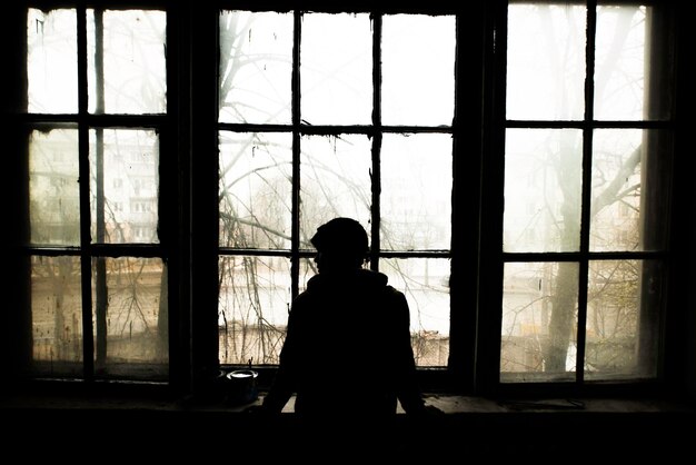 Silhouette einer Person, die durch das Fenster schaut