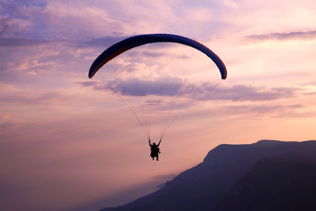 Silhouette einer Person, die während des Sonnenuntergangs gegen den Himmel paraglidet