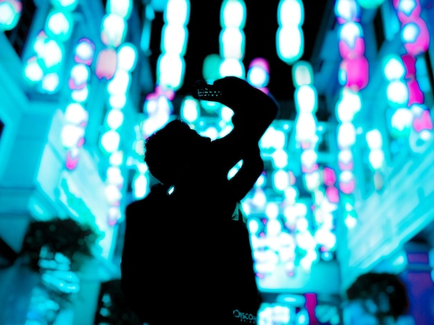 Silhouette einer Person gegen beleuchtete Lichter in der Nacht