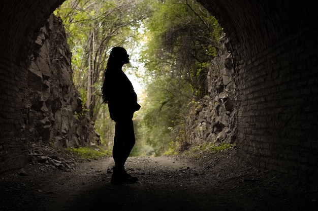 Silhouette einer schwangeren Frau, die ihren Bauch hält Porträt Natur Hintergrund im Freien