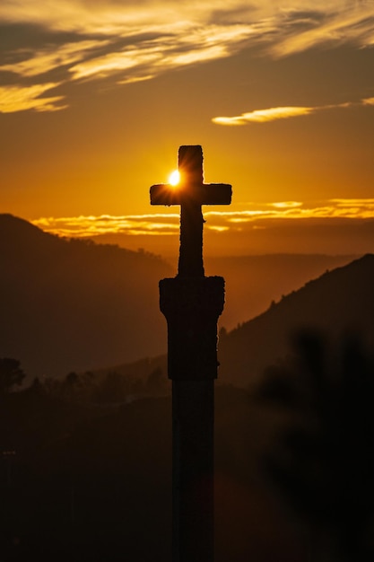 Foto silhouette eines der zahlreichen mittelalterlichen cruzeiros in ourense vor einem orangefarbenen himmel