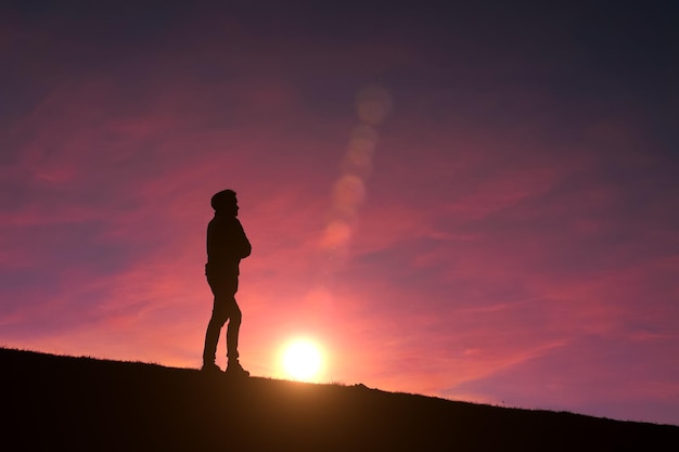 Silhouette eines erwachsenen Mannes im Berg mit einem romantischen Sonnenuntergang im Hintergrund