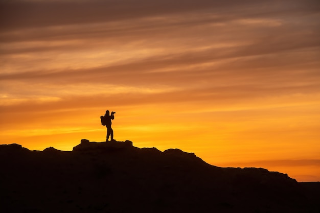 Silhouette eines Fotografen auf der Draufsicht bei Sonnenuntergang, Fotograf, der ein Foto auf dem Sonnenuntergangsberg macht