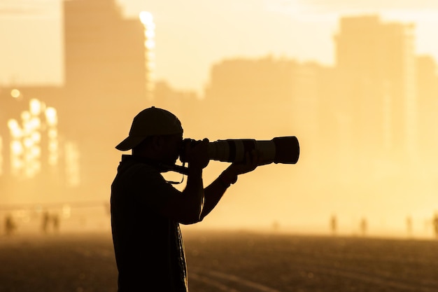 Silhouette eines Fotografen mit einem wunderschönen Sonnenaufgang im Hintergrund am Strand von Leblon in Rio de Janeiro