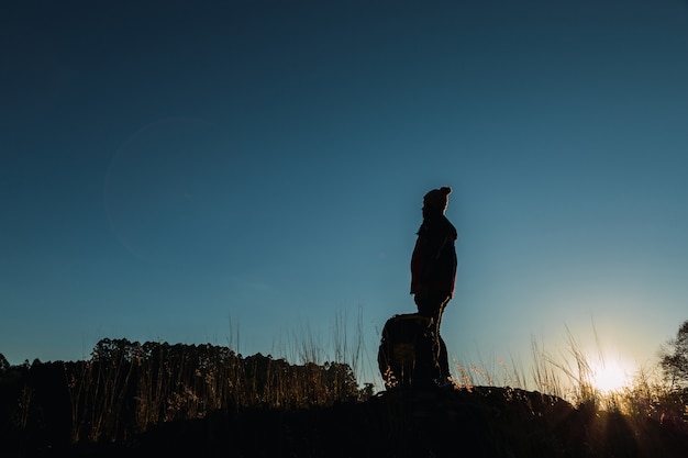 Silhouette eines Frauenwanderers an der Spitze eines Hügels.