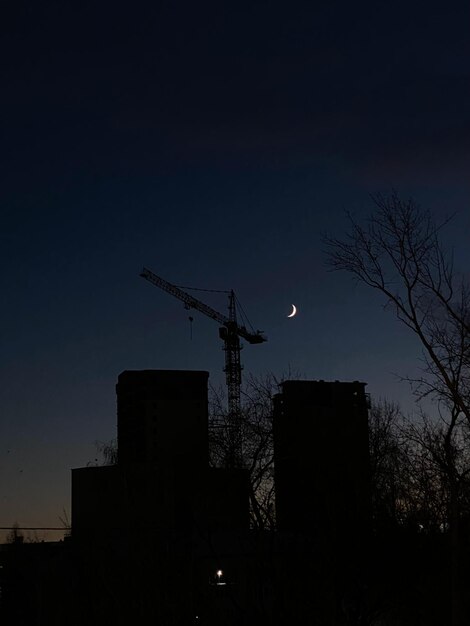 Foto silhouette eines gebäudes mit einem kran und einer mondsichel