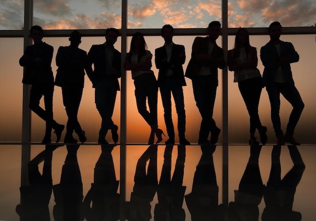 Silhouette eines Geschäftsteams, das neben dem Bürofensterfoto mit Kopierraum steht