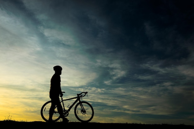 Silhouette eines gutaussehenden mannes mit fahrrad auf dem sunsetsport-mann-konzept