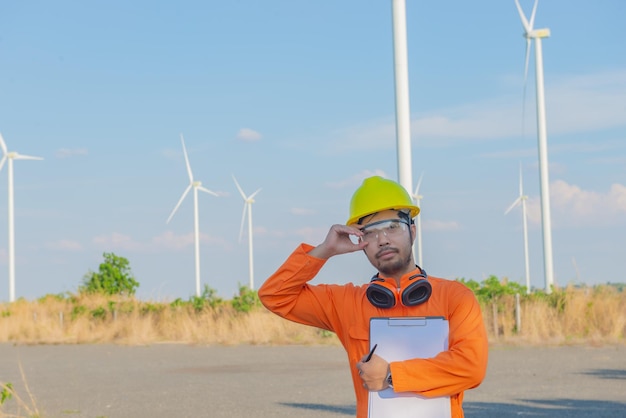 Silhouette eines Ingenieurs, der arbeitet und den Bericht in der Windturbinenfarm Power Generator Station auf den Menschen in MountainThailand hält