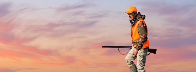 Silhouette eines Jägers mit einer Waffe gegen die Sonne ein Hinterhalt für Enten