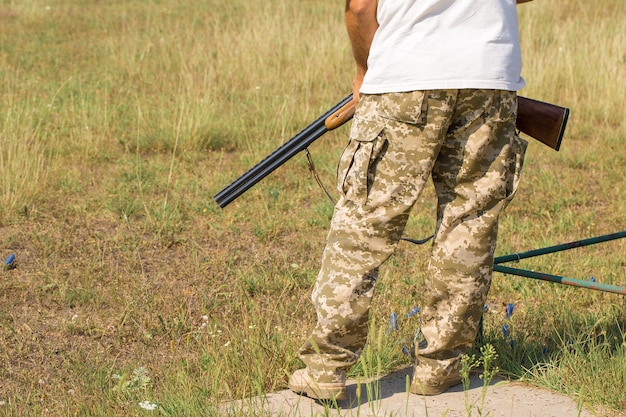 Silhouette eines Jägers mit einer Waffe im Schilf gegen die Sonne, ein Hinterhalt für Enten mit Hunden