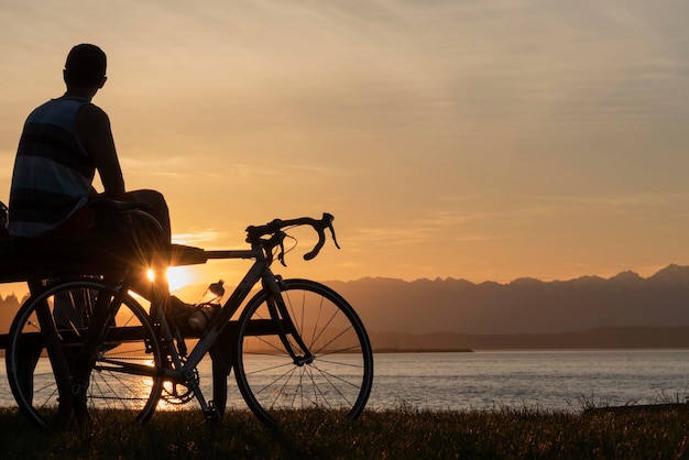 Silhouette eines Mannes auf einem Fahrrad am Meer gegen den Himmel bei Sonnenuntergang