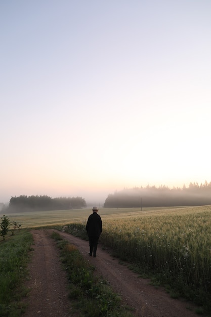 Silhouette eines Mannes, der bei Sonnenaufgang in einer malerischen Landschaft spazieren geht