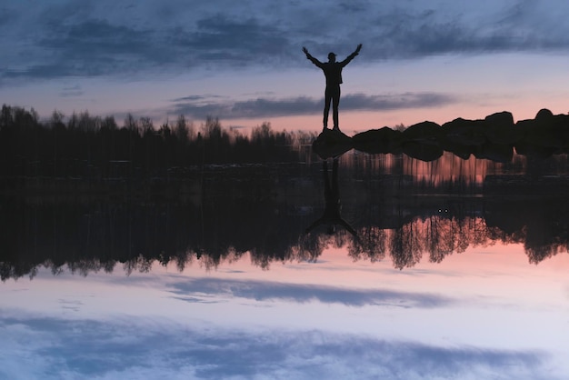 Foto silhouette eines mannes, der bei sonnenuntergang am ufer des sees gegen den himmel steht