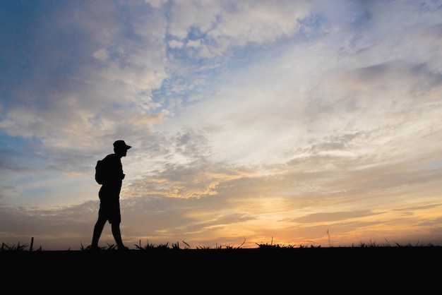 Silhouette eines Mannes, der bei Sonnenuntergang glücklich geht.