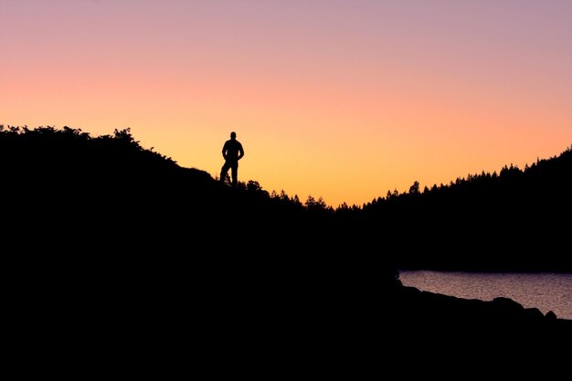 Foto silhouette eines mannes, der bei sonnenuntergang vor einem klaren himmel neben einem baum steht