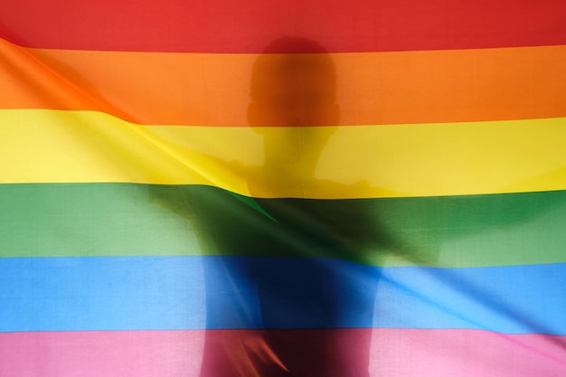 Silhouette eines Mannes, der eine Gay-Pride-Regenbogenfahne hält