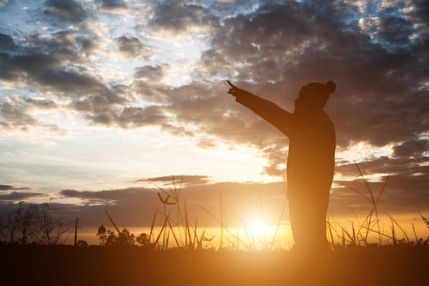 Foto silhouette eines mannes, der während des sonnenuntergangs auf dem feld gegen den himmel steht