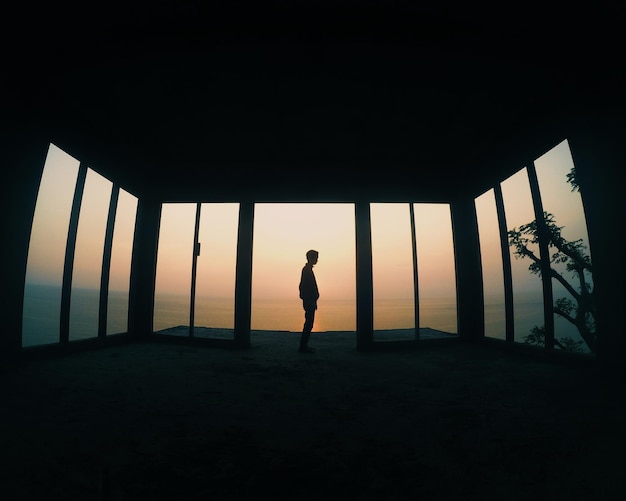 Silhouette eines Mannes, der während des Sonnenuntergangs in einer gebauten Struktur gegen den Himmel steht
