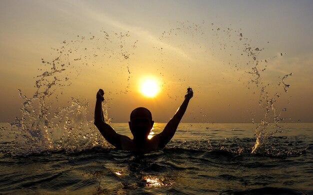 Foto silhouette eines mannes im meer gegen den himmel bei sonnenuntergang