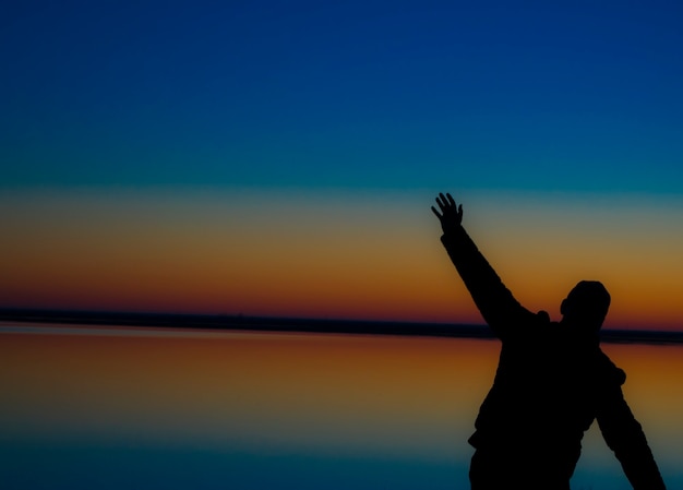 Foto silhouette eines mannes mit erhobenen händen bei sonnenuntergang der beginn eines neuen tages und eines neuen lebens