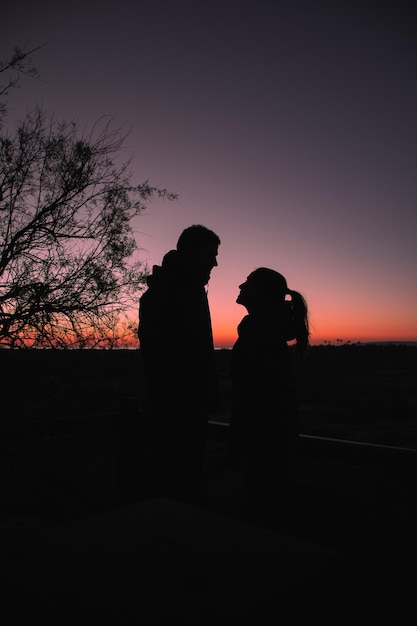 Silhouette eines Mannes und einer Frau, die den Sonnenaufgang am Strand genießen