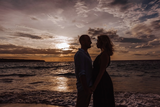 Silhouette eines Mannes und einer Frau gegen die Wand des Sonnenuntergangs