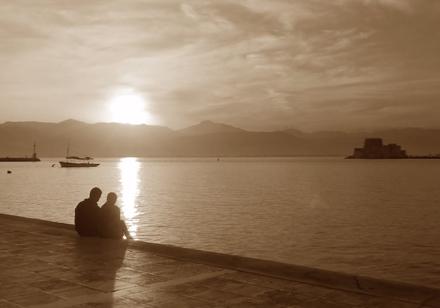 Silhouette eines Paares an der Strandpromenade bei Sonnenuntergang in Sepia-Ton