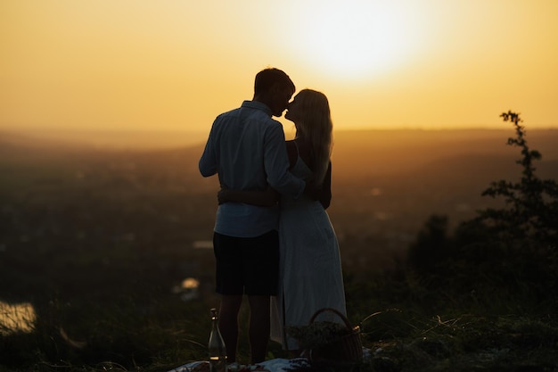 Silhouette eines romantischen Paares, das sich küsst, während es auf einem Hügel steht