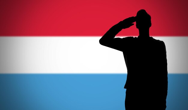 Foto silhouette eines soldaten, der gegen die luxemburgische flagge grüßt