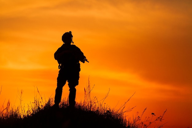 Silhouette eines Soldaten oder Offiziers mit Waffen bei Sonnenuntergang