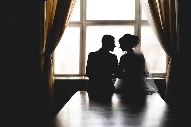 Silhouette eines verliebten Hochzeitspaares in der Nähe des Fensters