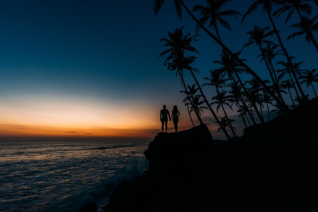 Silhouette eines verliebten Paares am Strand. Mann und Frau bei Sonnenuntergang. Flitterwochen auf den Inseln. Mann und Frau treffen Sonnenuntergang. Glückliches Liebespaar. Silhouette-Liebhaber. Flitterwochen. Händchen halten