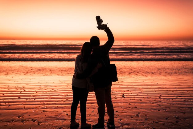 Silhouette eines verliebten Paares, das sich bei Sonnenuntergang am Strand umarmt