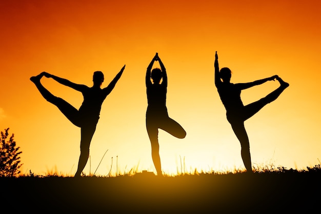 Silhouette eines Yogis bei Sonnenuntergang. Übungen für das Gleichgewicht.