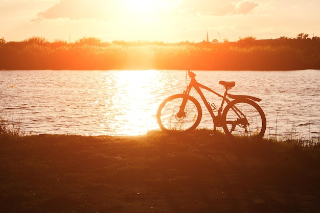 Silhouette Fahrrad vor Hintergrund Fluss und leuchtend roten Sonnenuntergang