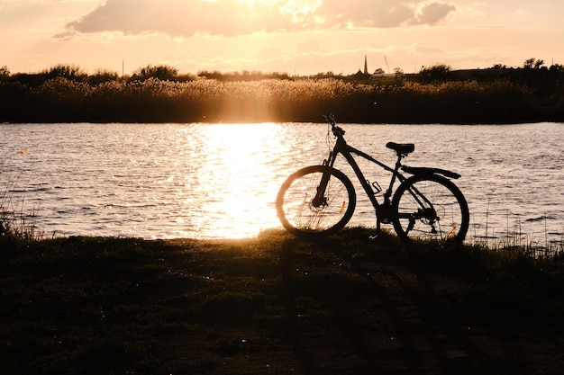 Silhouette Fahrrad vor Hintergrund Fluss und leuchtend roten Sonnenuntergang