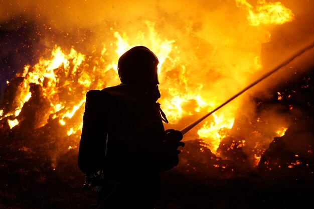 Foto silhouette feuerwehrmann gegen feuer in der nacht